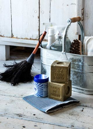 Metal cleaning caddy with cleaning products, cloths and a feather duster to illustrate spring cleaning tools