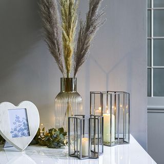 Glass vase, with two glass candle holders on a white table