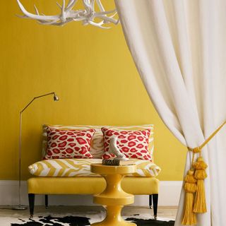 room with yellow wall yellow seat with red and yellow designed cushion and chandelier