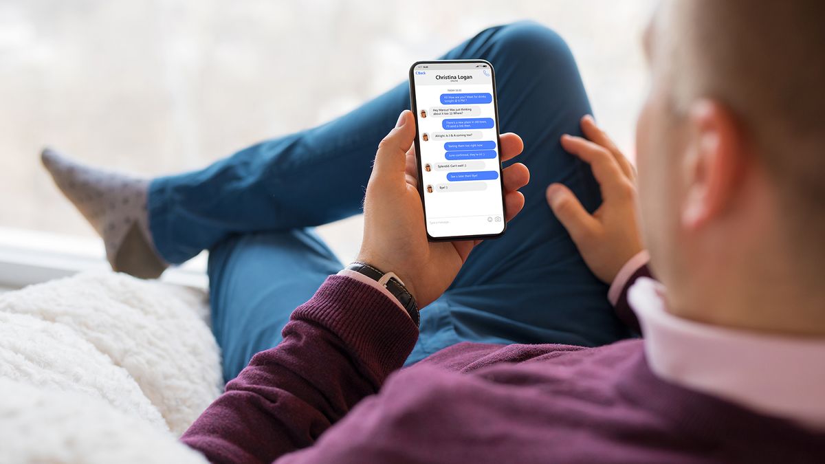 Person checking their phone with iMessage chat bubbles on their phone screen.