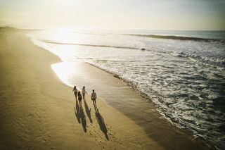 young family walking along a beach at sunset