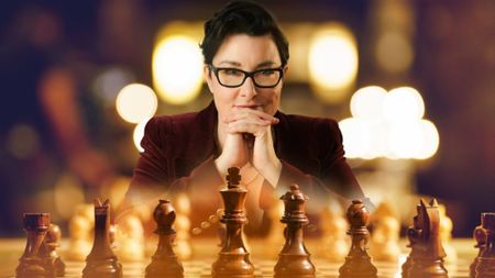 Sue Perkins facing a chess board as the host of BBC Two's reality gameshow Chess Masters: The Endgame. 