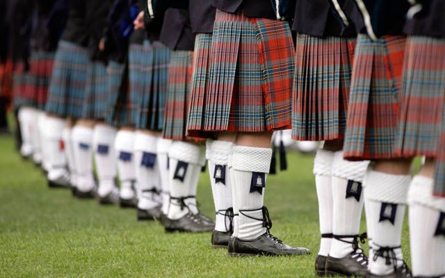 A row of men wearing traditional Scottish kilts.