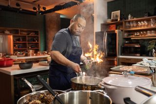 david chang cooks over a stove with many pots and flames in the netflix show dinner time live with david chang