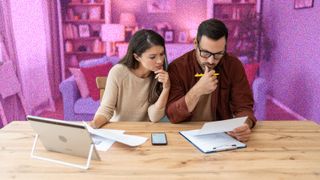 Young couple looking at bills sitting at kitchen table