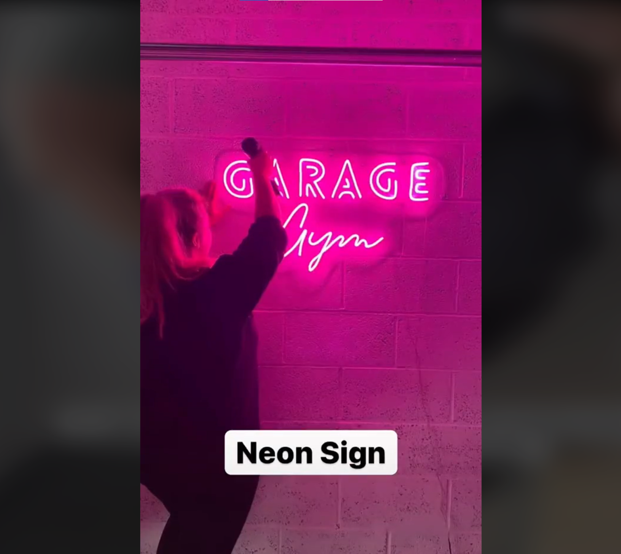 Jasmine putting up neon lights whilst being pregnant which read Garage in pink colouring