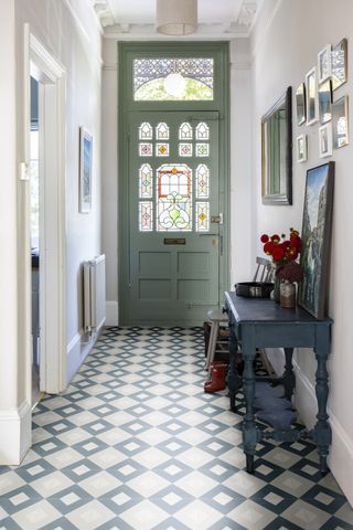 Sage painted door in a hallway with bold geometric tiles