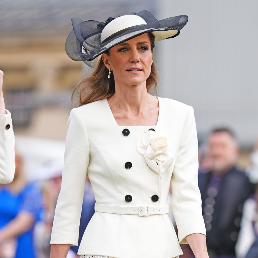 Kate Middleton wears a pleated polka-dot skirt with a white peplum jacket and beige heels.