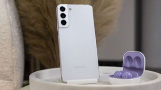 Samsung Galaxy S22 in purple standing upright with Galaxy Buds in purple