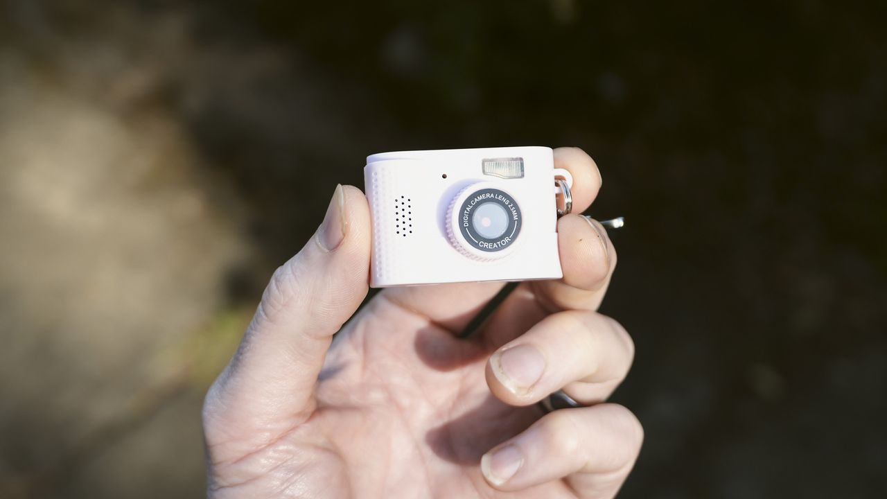 Miniature pink keychain camera, the 'Photo Creator Mini Digital Camera series 3', in user's hand