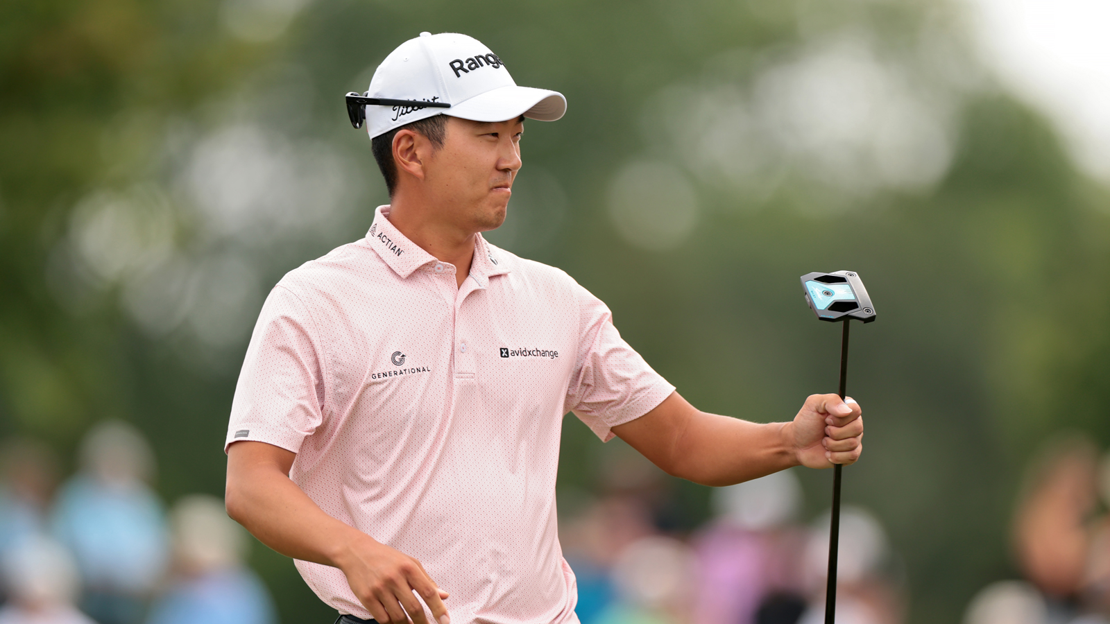 Michael Kim fist pumps while holding a putter