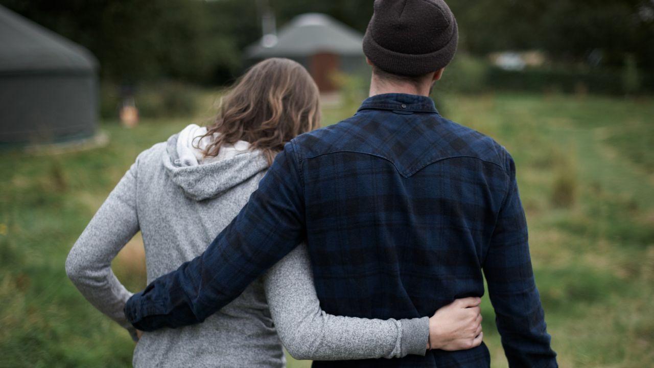 Couple with backs to camera, arms around each other&#039;s waists