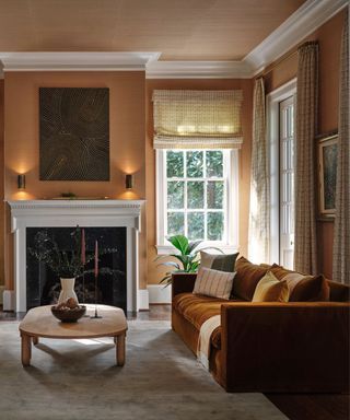 A orange-brown living room with a velvet sofa and white fireplace