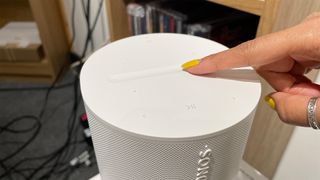 Close up of a finger sliding along touch controls on top of Sonos Era 100 wireless speaker