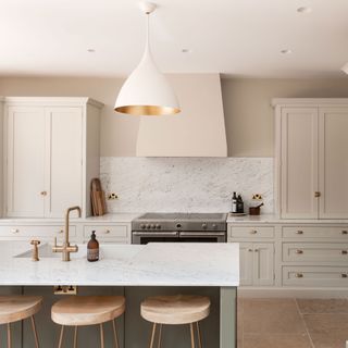 Cream coloured kitchen with a kitchen island and bar stools and range cooker