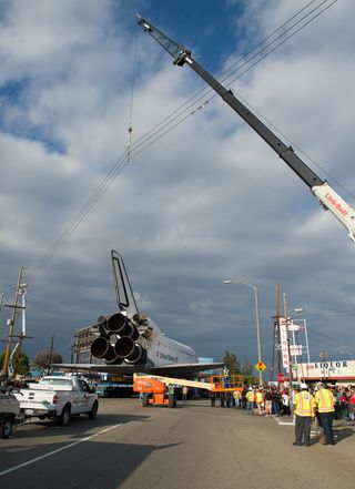 Power lines are hoisted upwards by a crane in order to allow the space shuttle Endeavour to traverse on its path to its new home at the California Science Center, Friday, Oct. 12, 2012 in Inglewood.