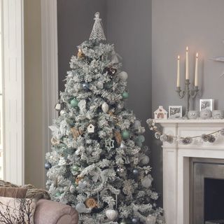 Christmas tree with white decorations and angel tree topper.