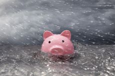Pink piggy bank partially submerged in turbulent water, stormy sky, wind blown rain