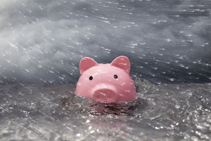Pink piggy bank partially submerged in turbulent water, stormy sky, wind blown rain