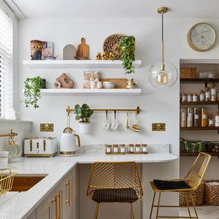 White painted kitchen with marble worktops, kitchen decorated with accessories and appliances with gold accents