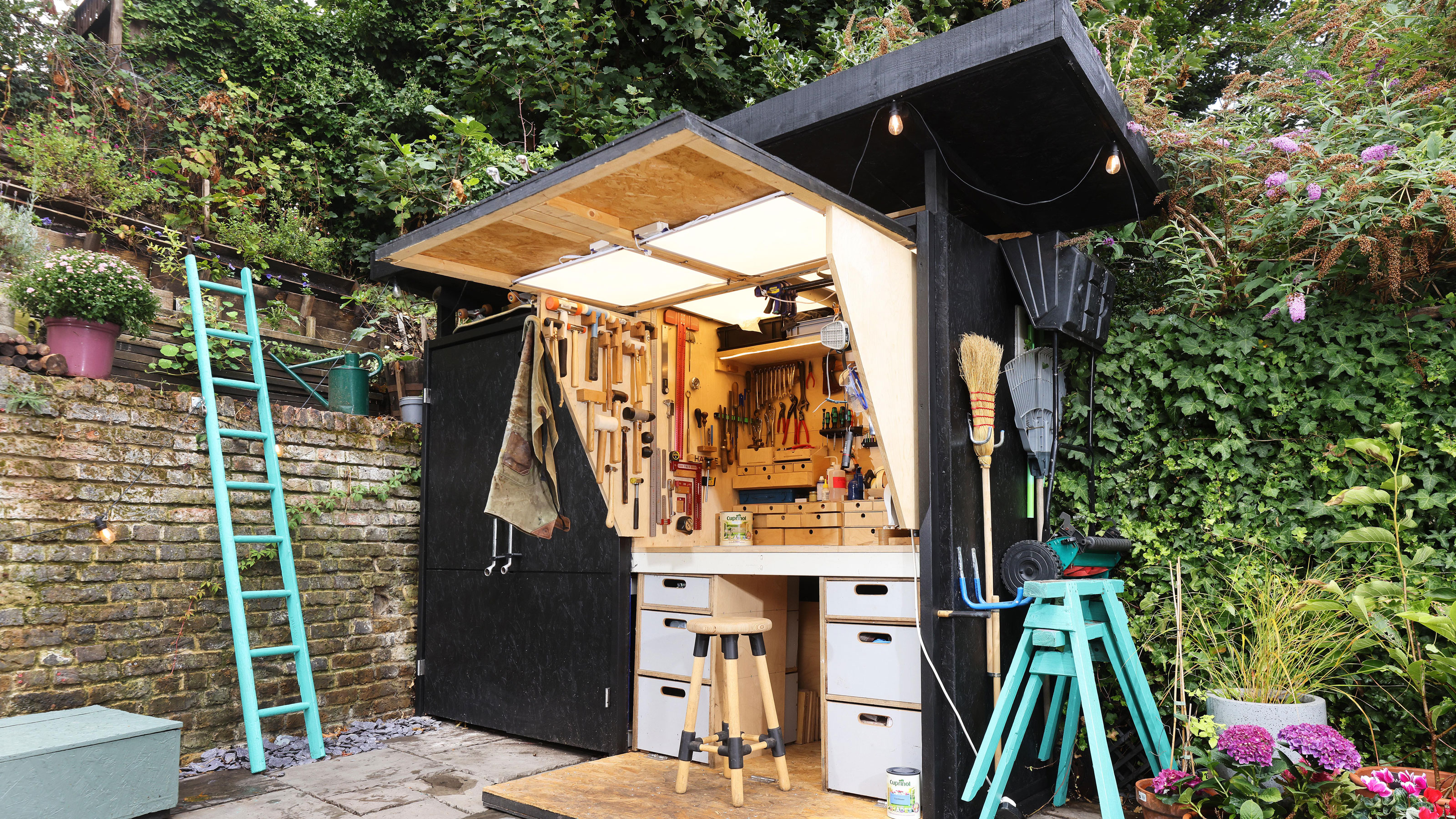 Cuprinol shed of the year in black with spanner handles and wooden workshop desk hidden inside