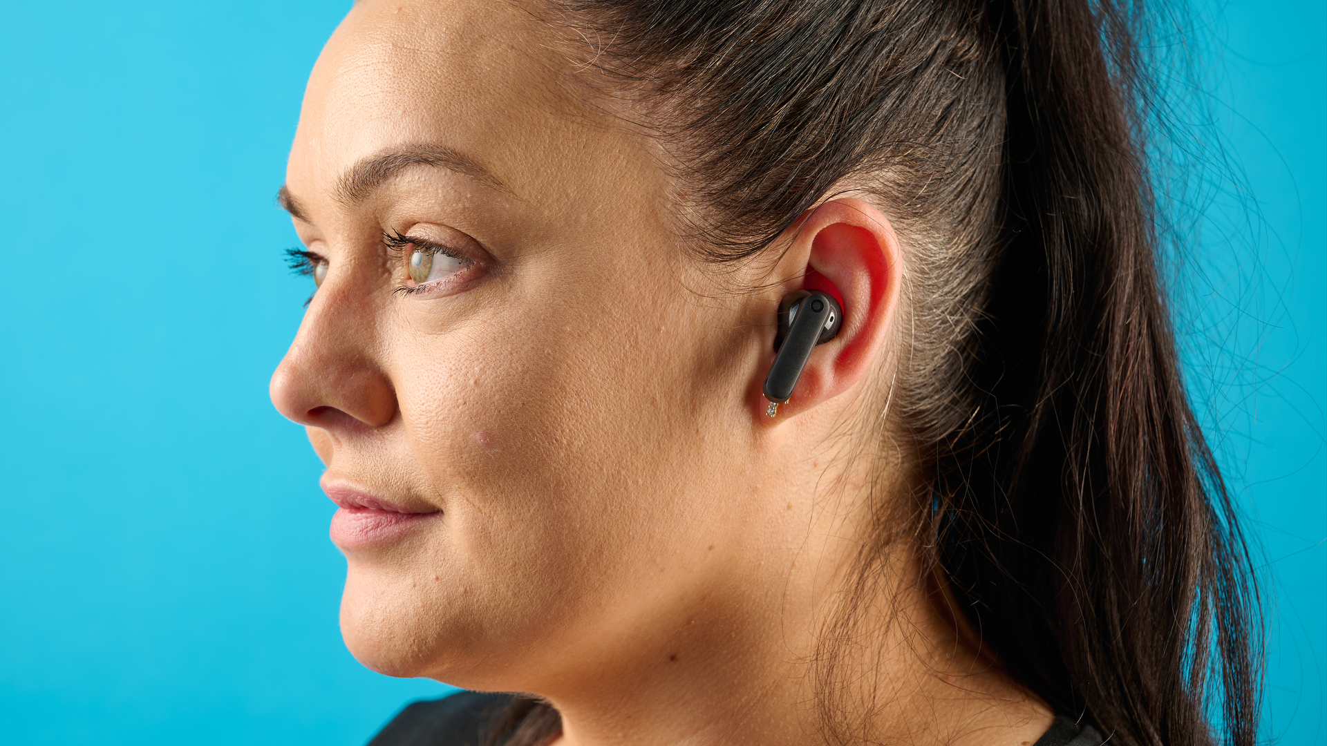 CMF Buds 2 in Dark Gray photographones on a gray table in front of a blue background