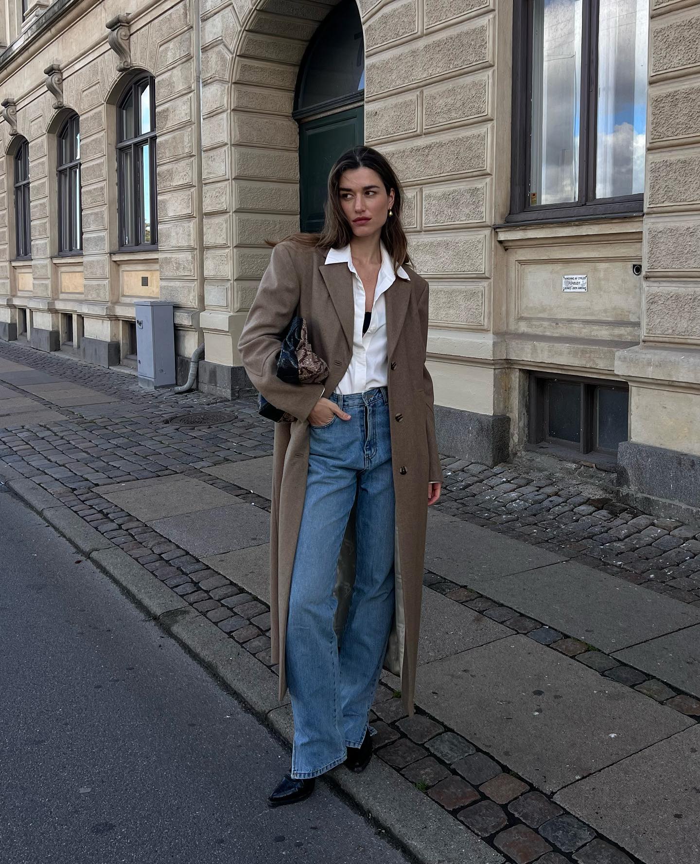 @iliridakrasniqi wears a brown frock coat with jeans and a white shirt