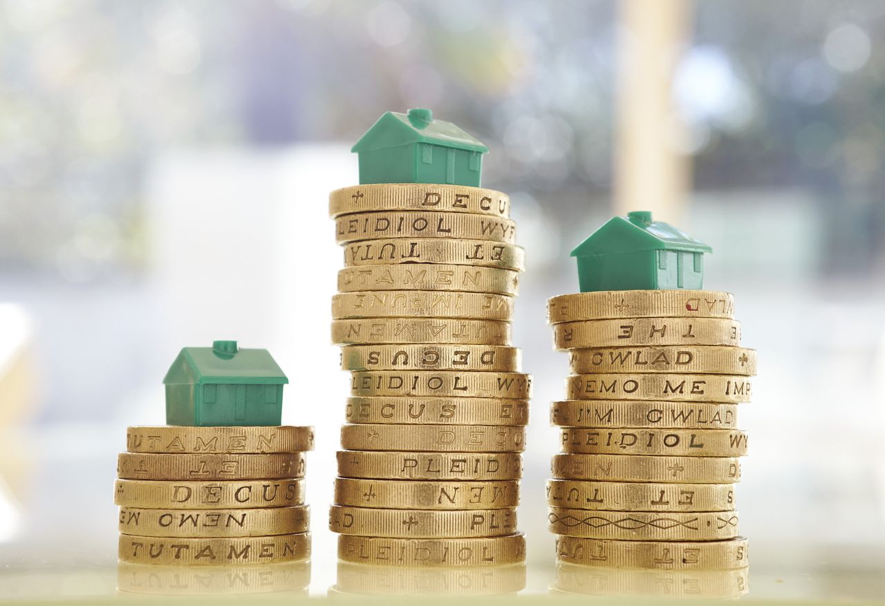 Stacks of British pound coins with model houses on them.