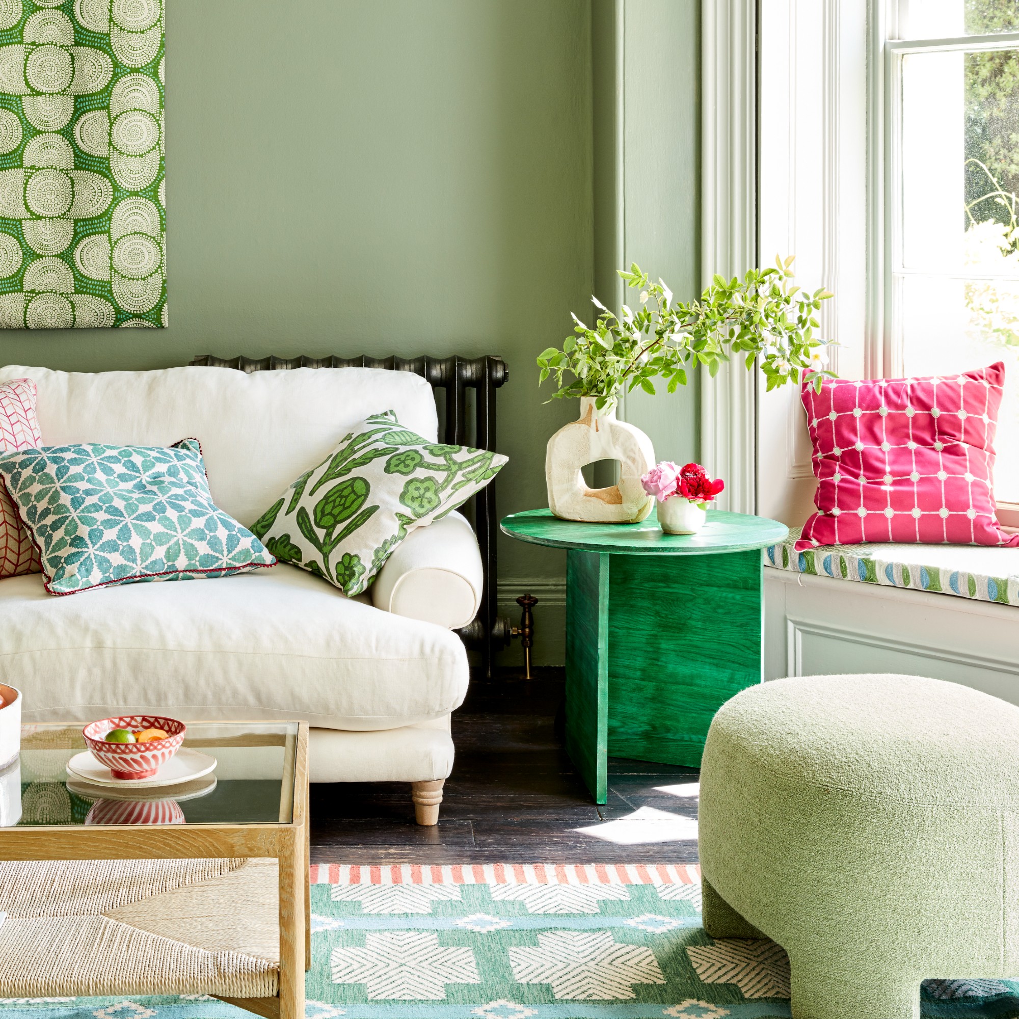 A green living room with a patterned window seat in the bay window