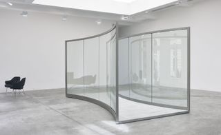 The work comprises two stainless steel curves holding two way mirrors.