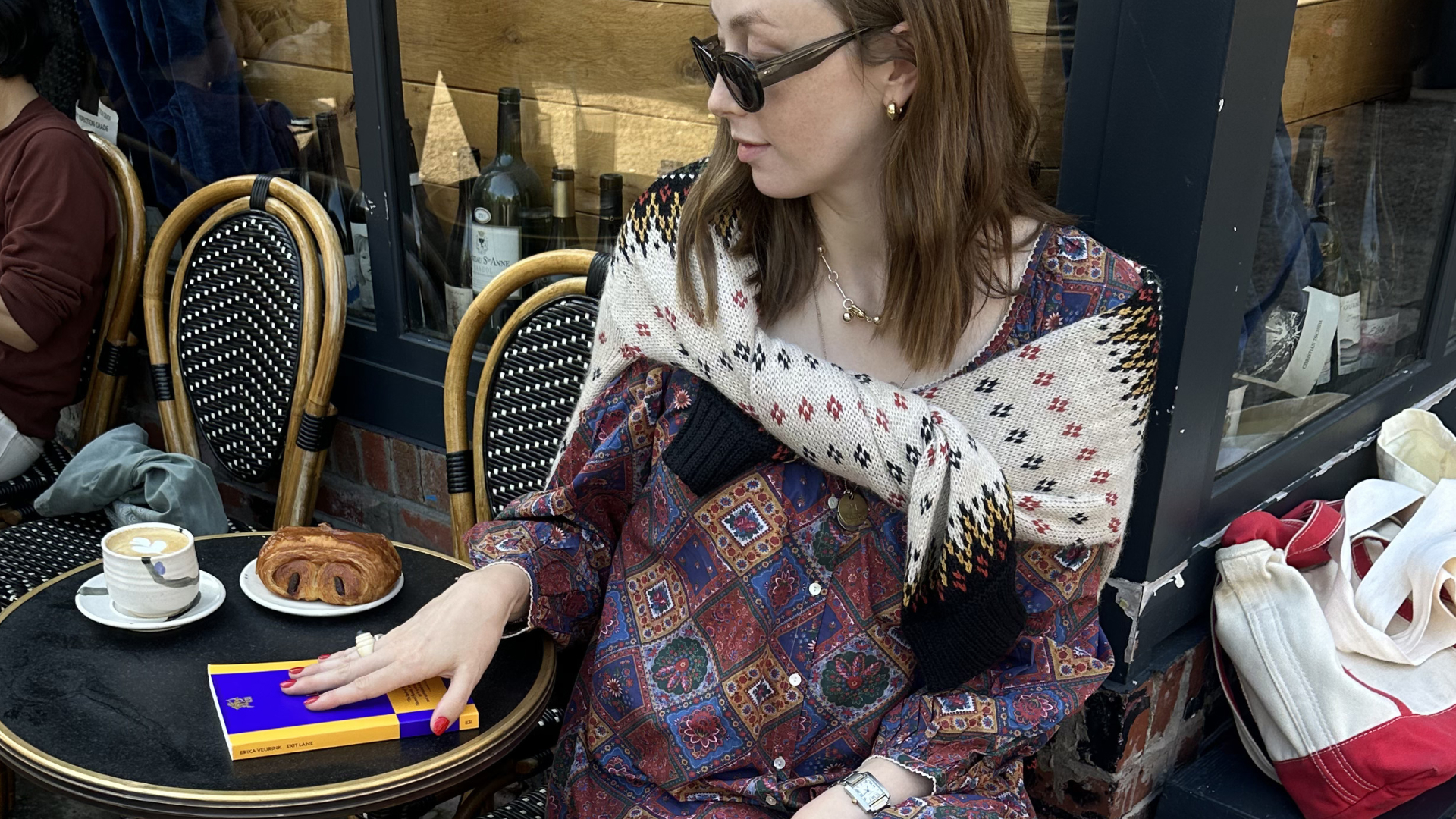 Erika Veurink posing with her debut novella at a cafe