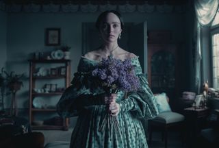 lily rose depp as ellen hutter in nosferatu holding a bouquet of purple flowers