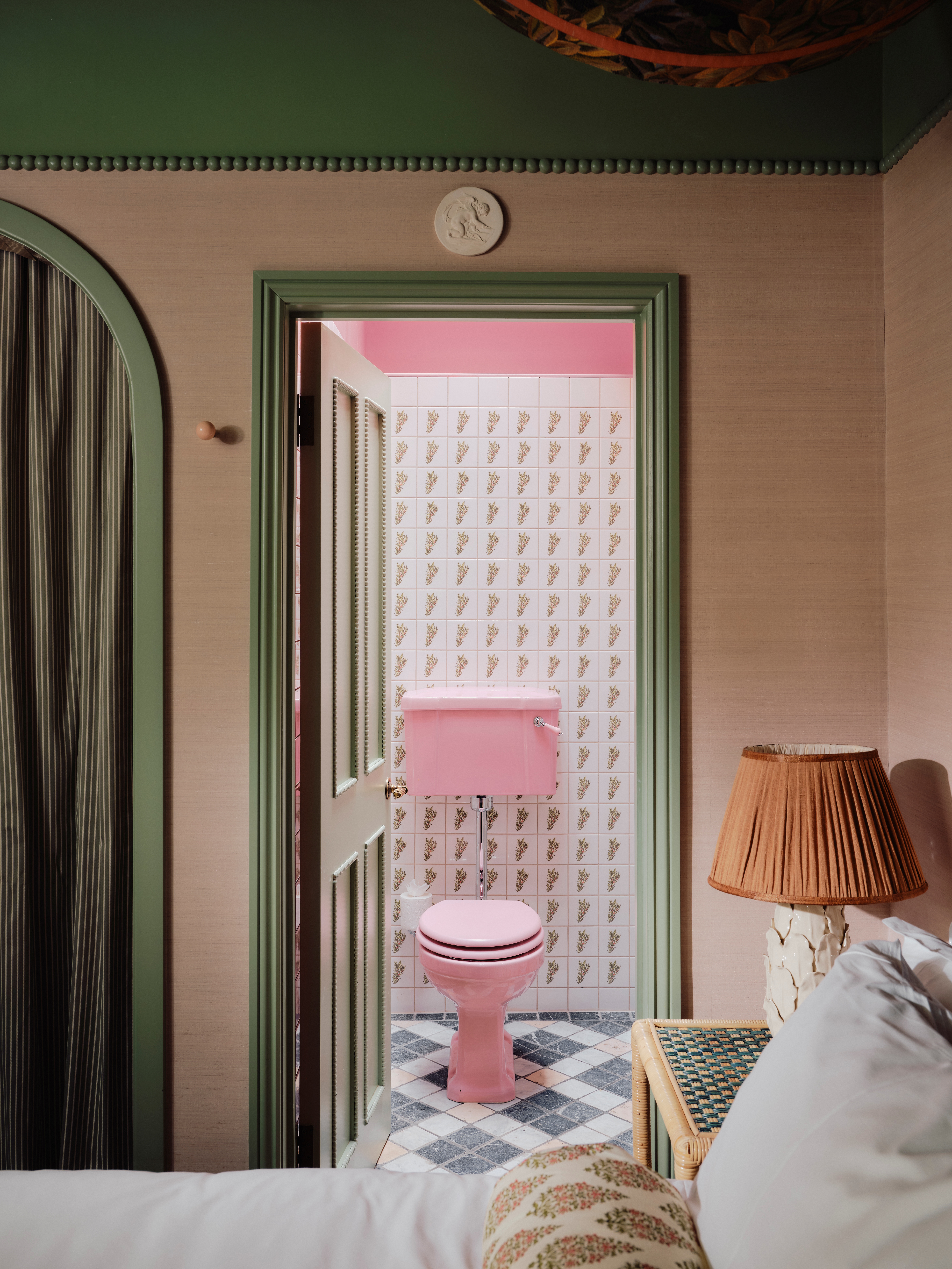 A maximalist hotel filled with tapestries, colorful tiling, velvety fabrics, artworks, and a pale green, pink, and red palette.