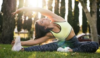 Woman stretching while practicing yoga in park