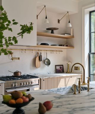 A neutral deVOL kitchen with a brass sink and marble countertops