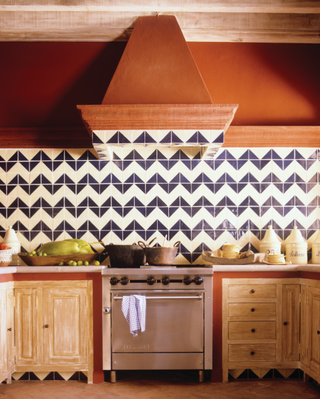 A kitchen with orange hood, and zig zag backsplash tiles