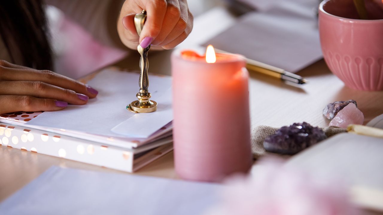 A woman stamping an envelope with sealing wax