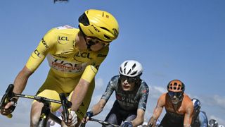 Tadej Pogacar wearing the overall leader's yellow jersey looks back as he cycles ahead of Jonas Vingegaard in Tour de France 2024