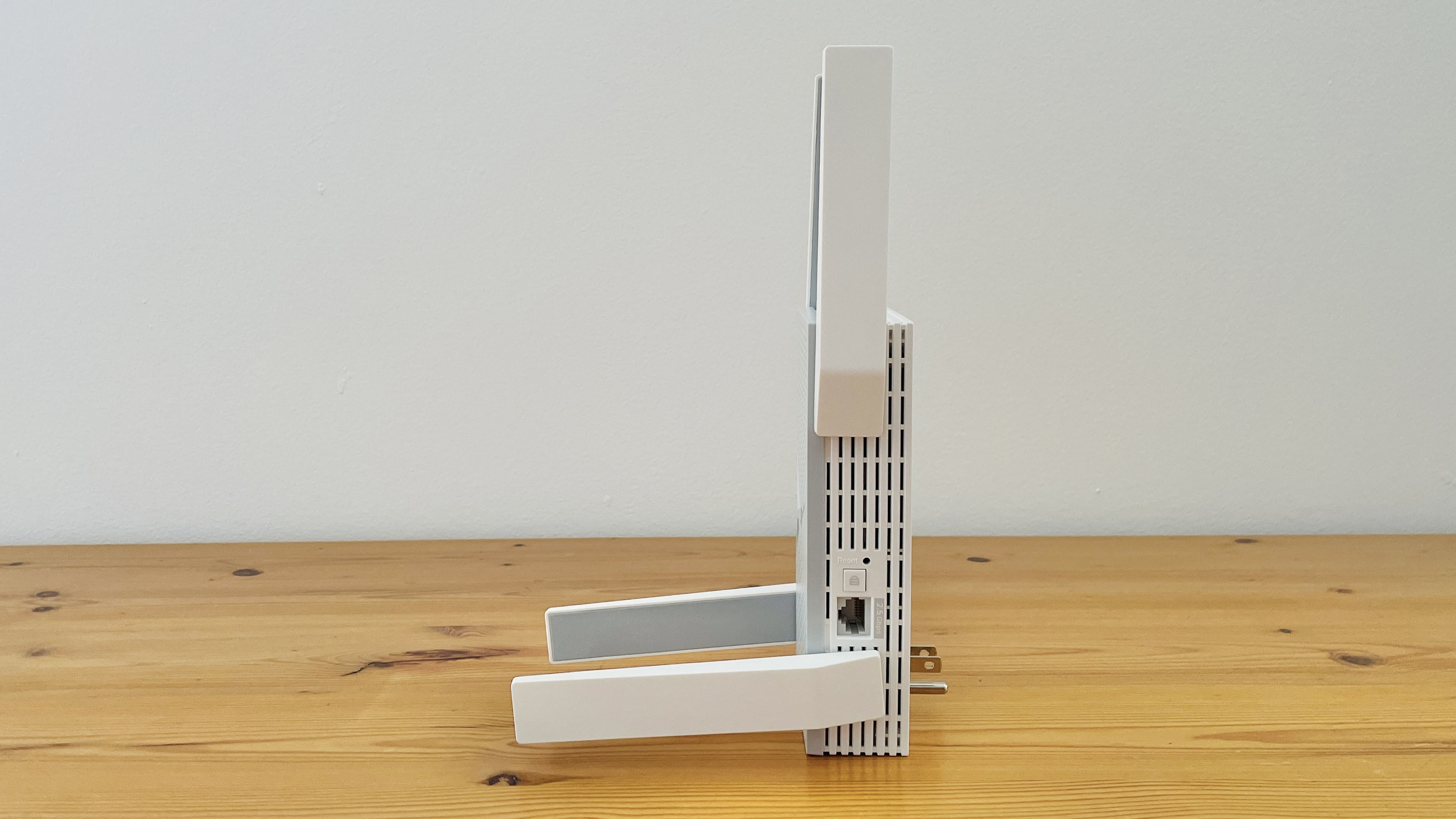 TP-Link BE10000 Wi-Fi range extender on wooden desk