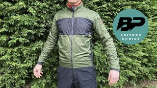 Man wearing gravel cycling jacket in front of hedge