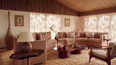 Image of a living room from above with a blush pink curved sofa and a beige shag rug. There are sheer curtains on the back window and in front of the sofa is a red circular nesting coffee table.