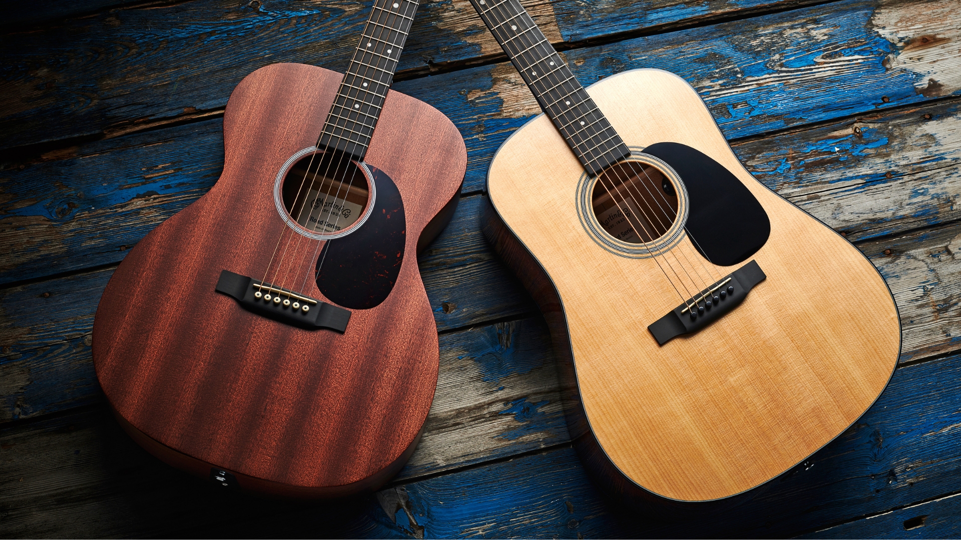 Two Martin acoustic guitars on a blue wooden floor