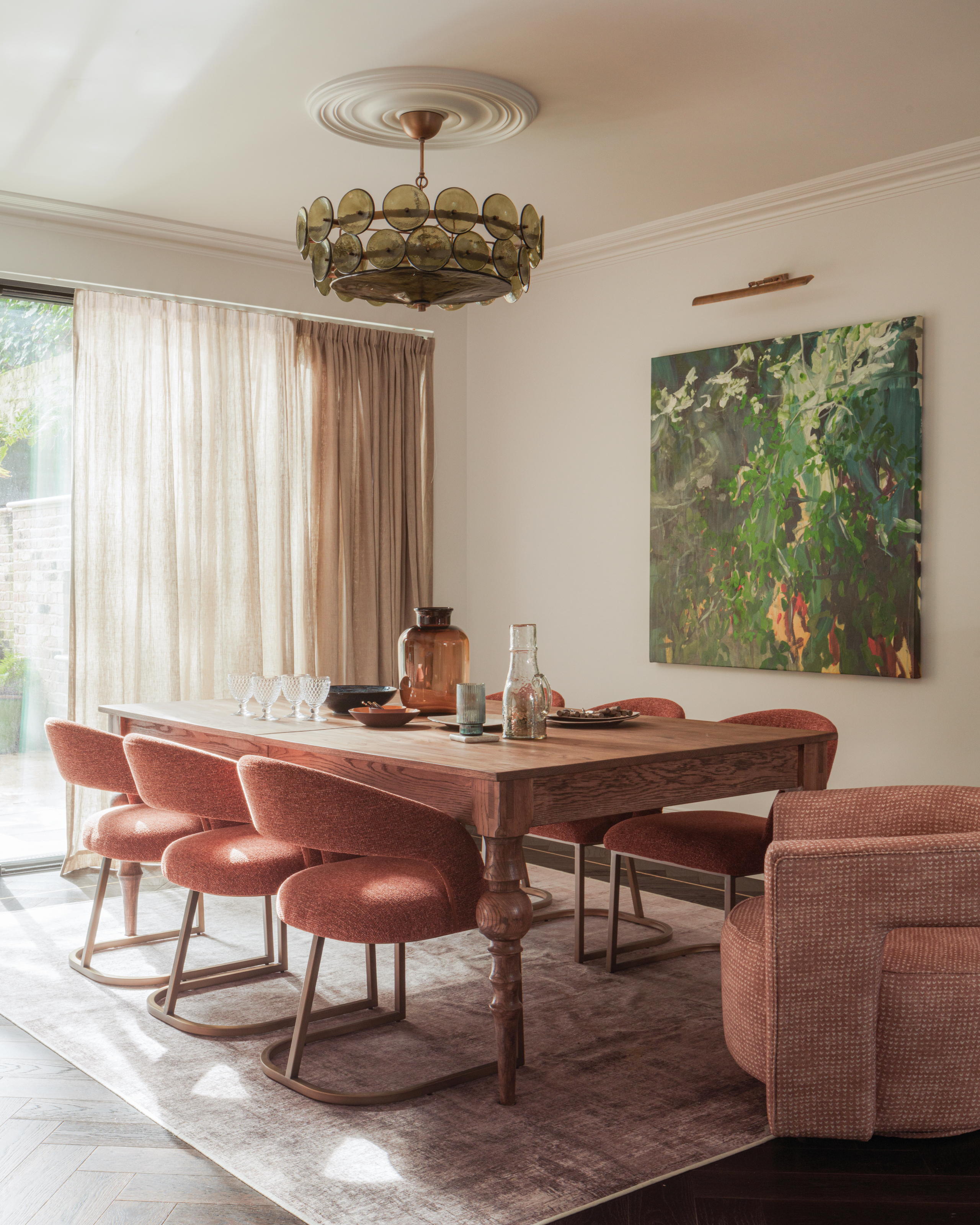Cream dining room with oak table, pink velvet dining chairs and green glass chandelier