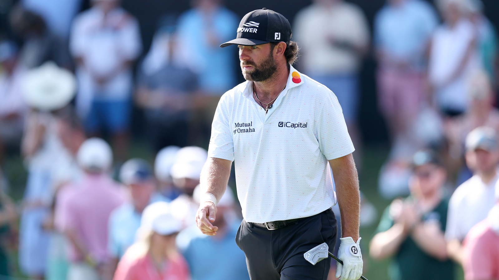 Cameron Young walks off the green holding a putter