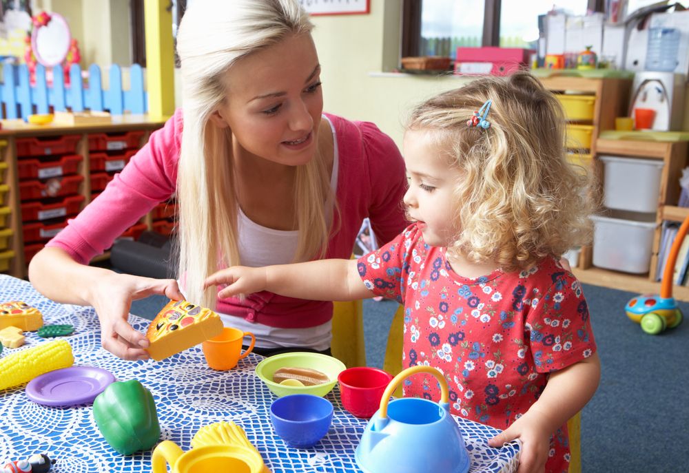 A little girl plays with her daycare teacher.