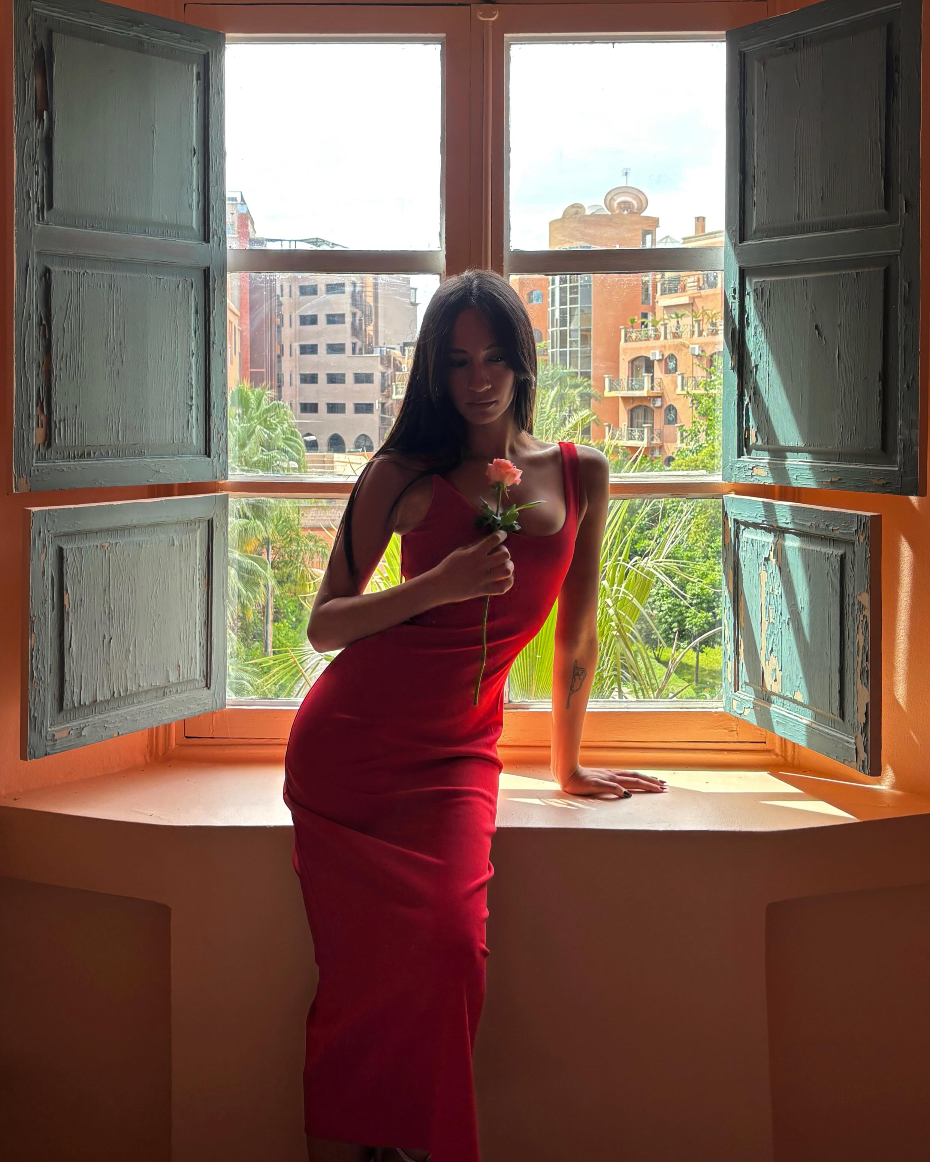 A woman in a red dress holding a rose.