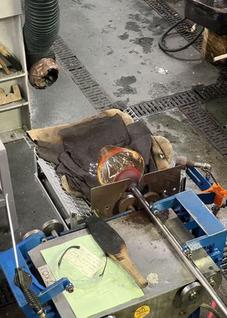 The glass blown into a unique shape being inspected in the factory.