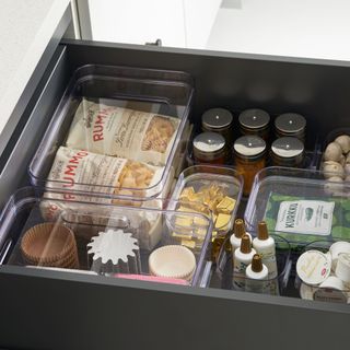 Black pull out kitchen drawer with contents organised in clear containers