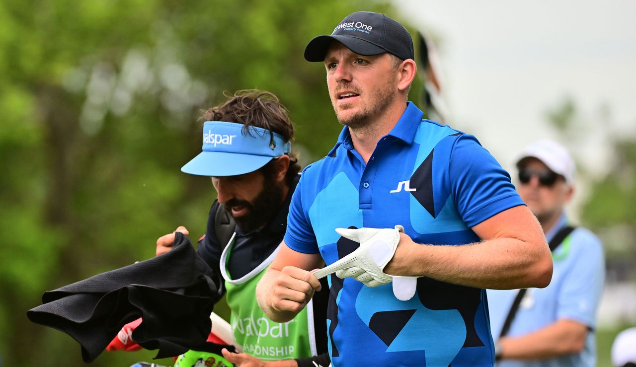 Wallace walks with his caddie whilst removing his golf glove