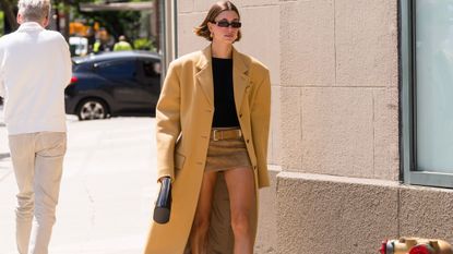 Hailey Bieber wears mini skirt and oversized Prada coat with loafers